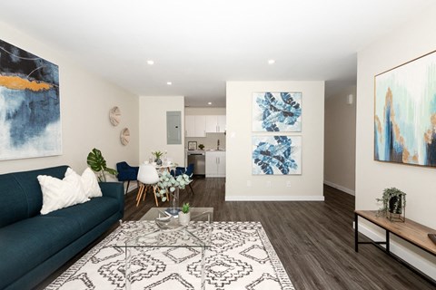 A living room with a blue couch and a large painting on the wall.