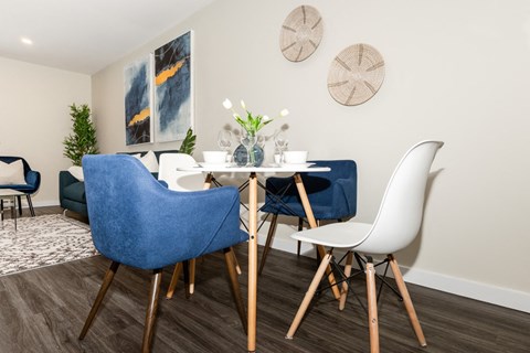 A dining room with a blue chair and white chairs.