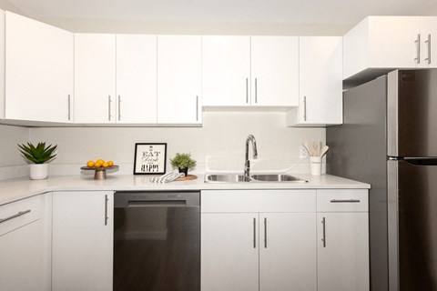 A modern kitchen with white cabinets and a black fridge.