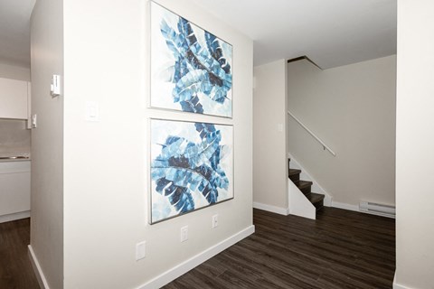 A hallway with two paintings on the wall and a staircase.