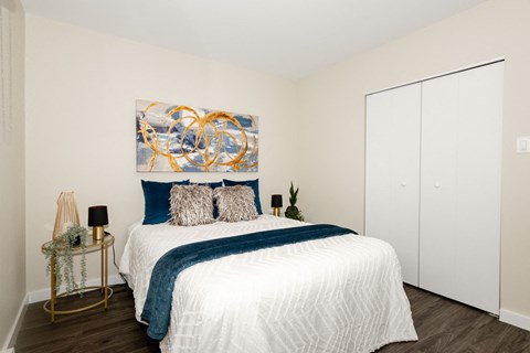A bedroom with a large bed and a painting on the wall.