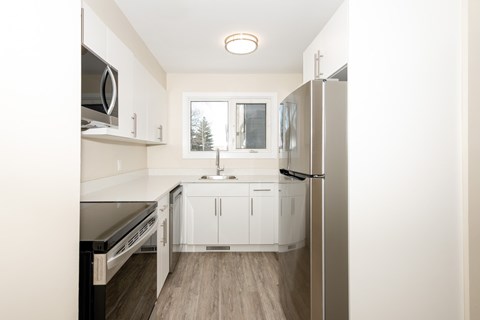 A kitchen with white cabinets and a refrigerator.