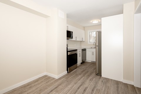 A kitchen with white cabinets and a wooden floor.