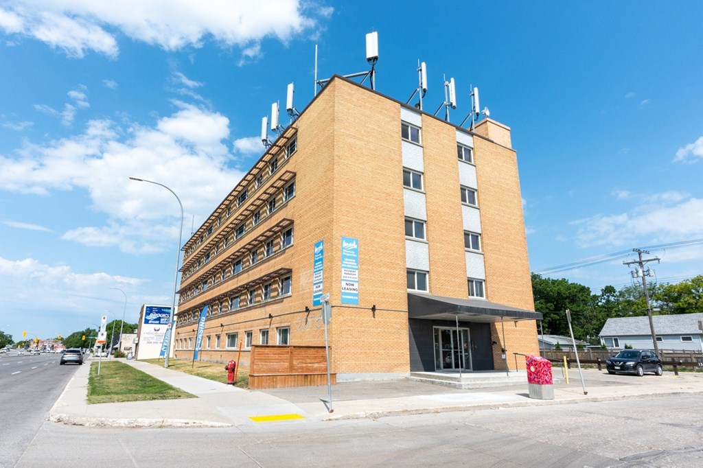 A large brick building with antennas on top and a blue sign in front.