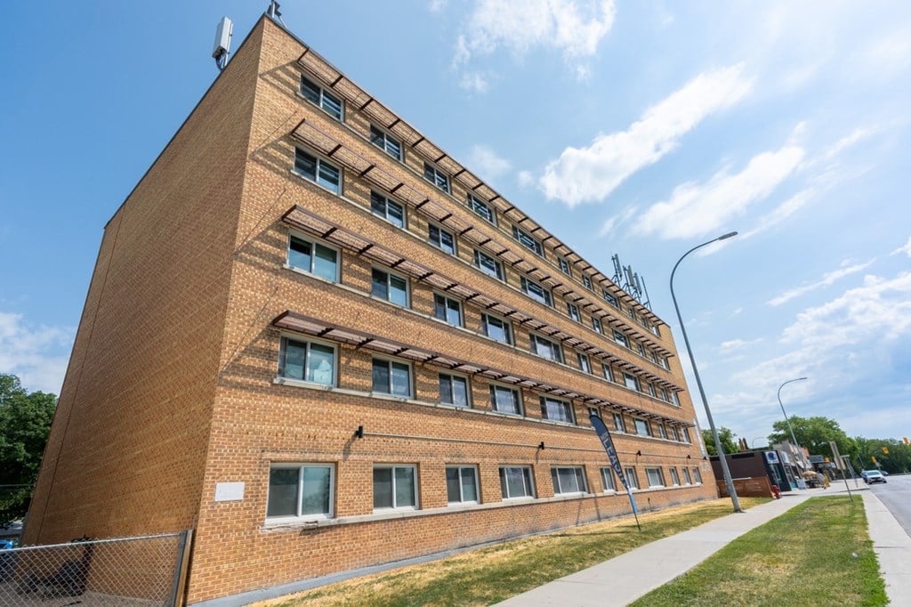 A tall brick building with a fence in front of it.