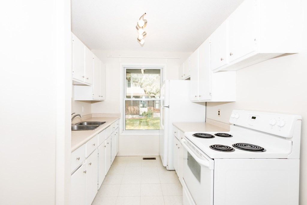 A white kitchen with a stove and sink.