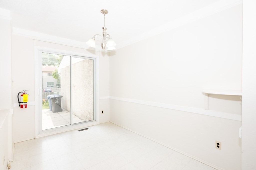 A white room with a door and a chandelier.