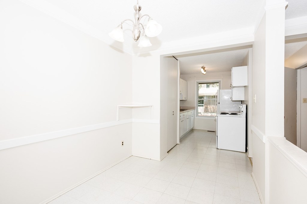 A white kitchen with a chandelier and a dining area.