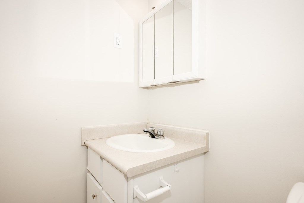 A white bathroom sink with a cabinet above it.