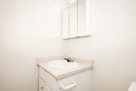 A white bathroom sink with a cabinet above it.