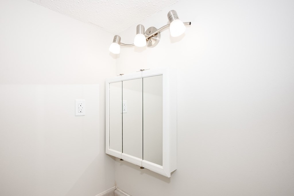 A white bathroom with a mirror and lights.