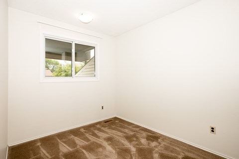 A room with a window and carpeted floor.