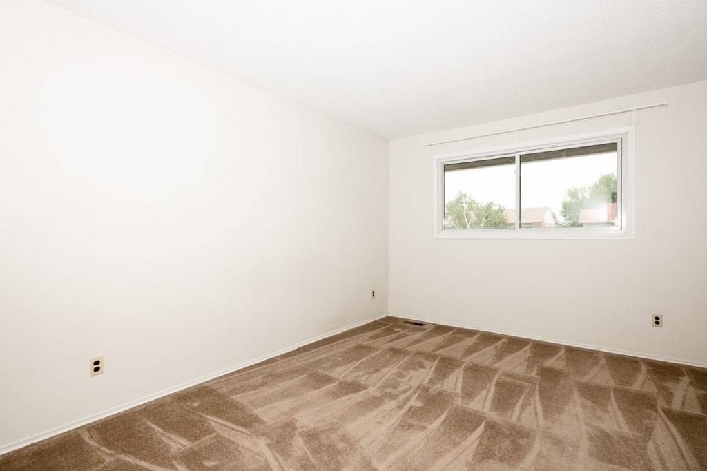 A room with a carpeted floor and a window.