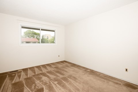 A room with a window and carpeted floor.