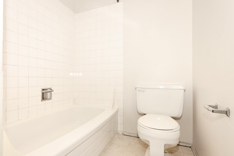 A white toilet sits next to a white bathtub in a bathroom.