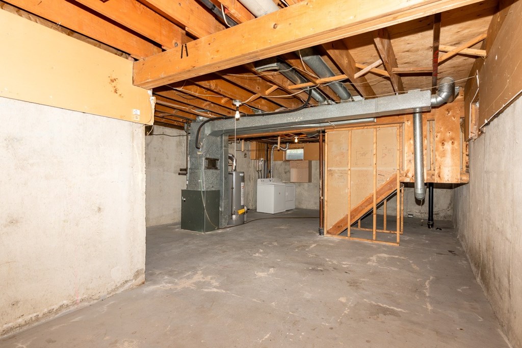 A room under construction with a staircase and a furnace.