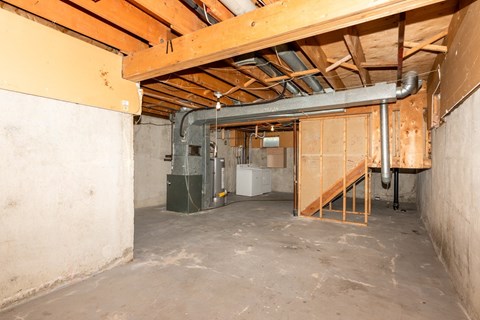 A room under construction with a staircase and a furnace.