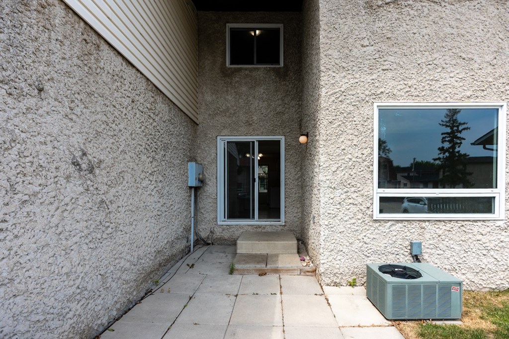A house with a grey wall and a window showing a tree.