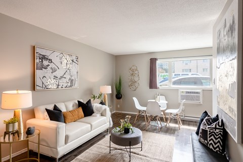 A living room with a white couch, a coffee table, and a large painting on the wall.