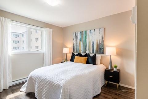 A bedroom with a large bed and two lamps.