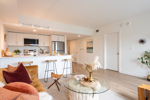 A modern kitchen with a bar stool and a glass table with a tray of food on it.