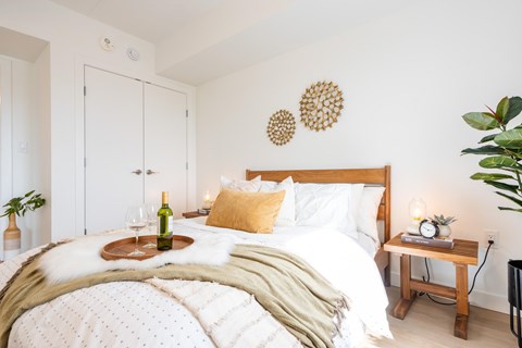 A cozy bedroom with a large bed and a tray with a bottle and glasses on it.