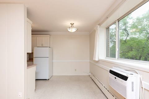 A white kitchen with a window and a white fridge.