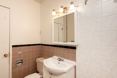 A bathroom with a toilet, sink, and mirror.