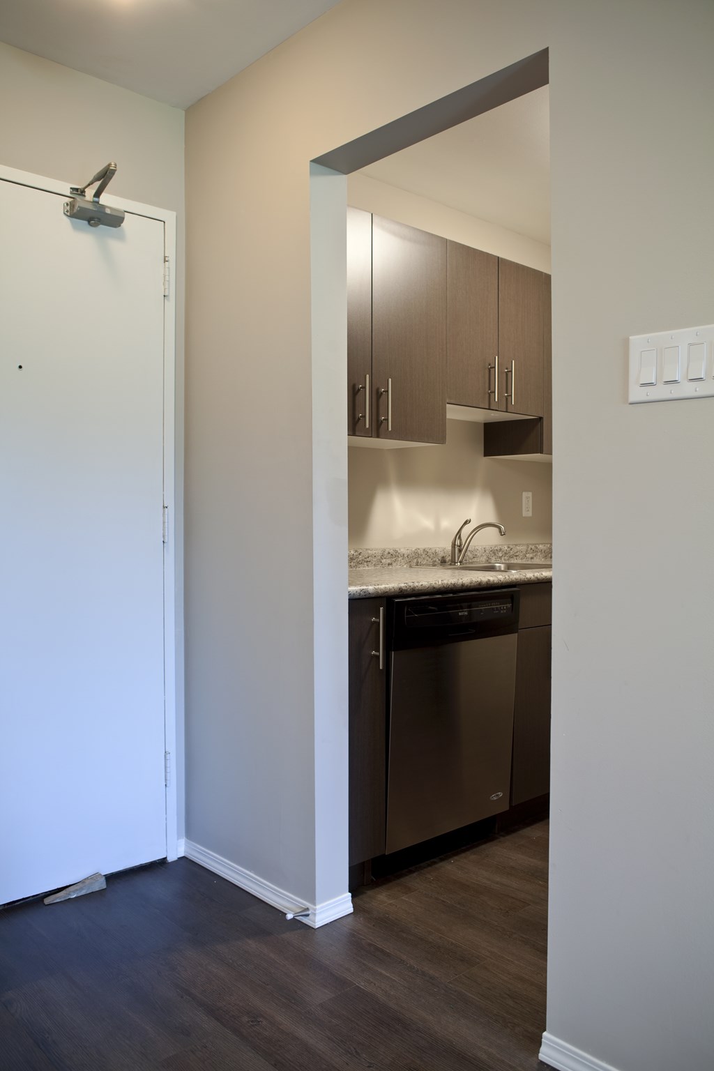 A kitchen with a white door and a white light switch.