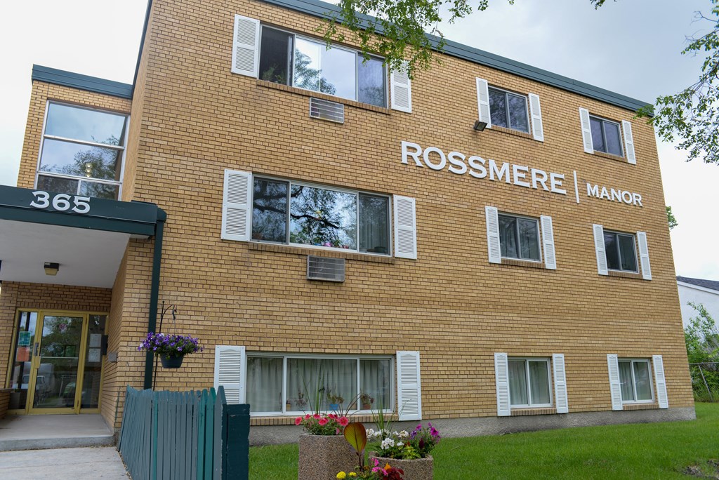 A brick building with the words Rossmere Manor on the side.