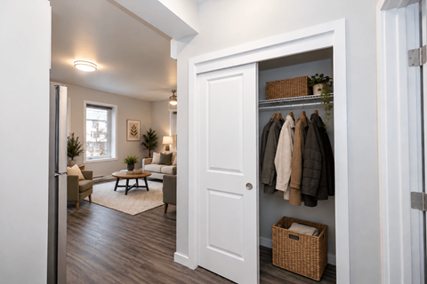 A white door is open to a hallway with a coat rack and a basket on the floor.