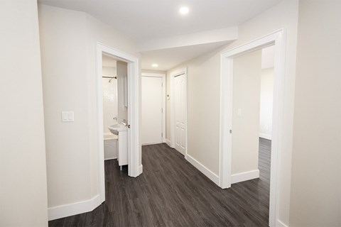 a hallway with white walls and hardwood floors