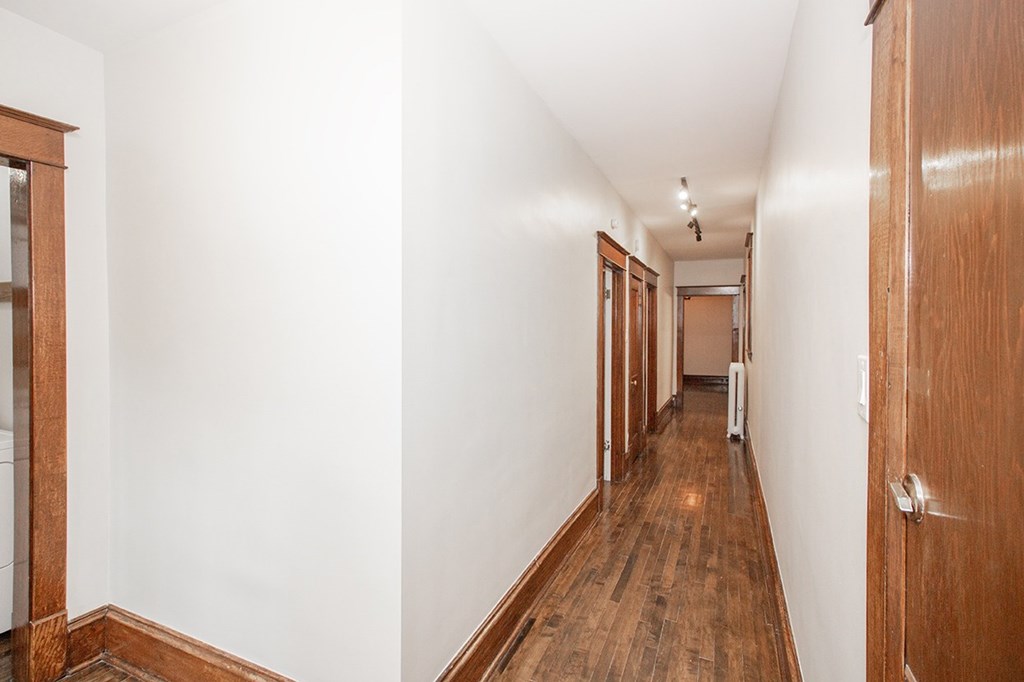 A long hallway with wooden floors and white walls.