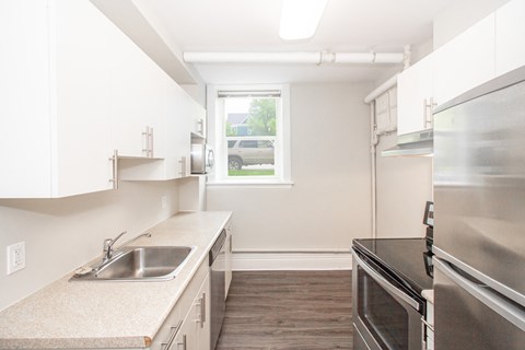 a kitchen with white cabinets and stainless steel appliances and a window