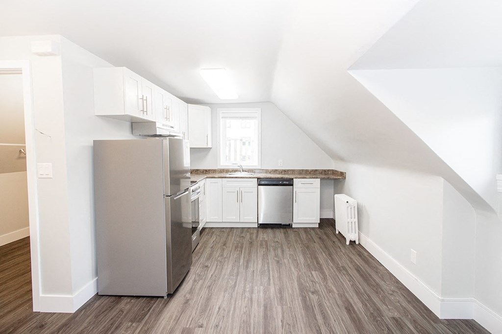 a small kitchen with white cabinets and a stainless steel refrigerator