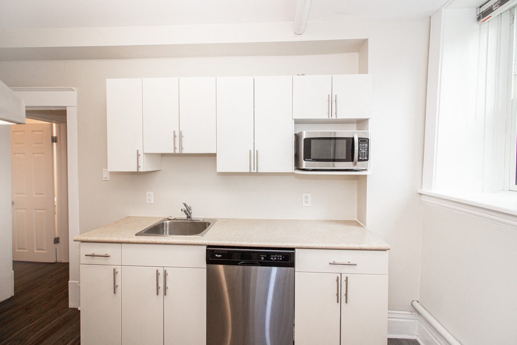 a kitchen with white cabinets and a stainless steel dishwasher