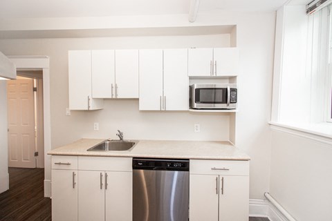 a kitchen with white cabinets and a stainless steel dishwasher