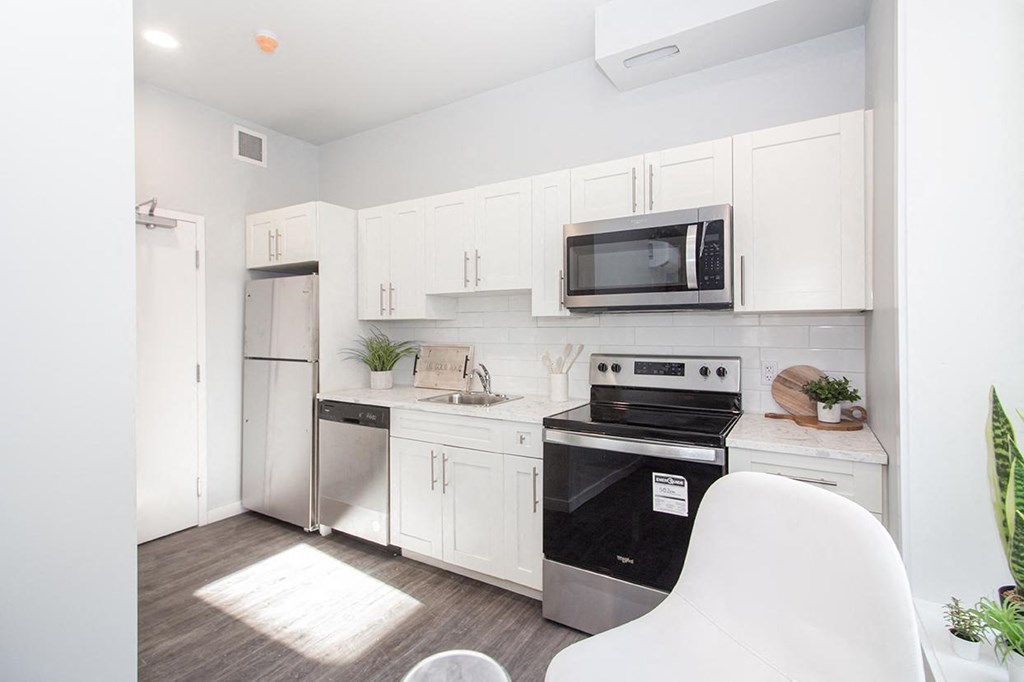 a kitchen with white cabinets and a black stove top oven for rent in Wpg
