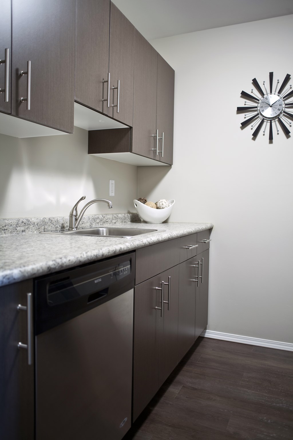 A modern kitchen with dark wood cabinets and stainless steel appliances.