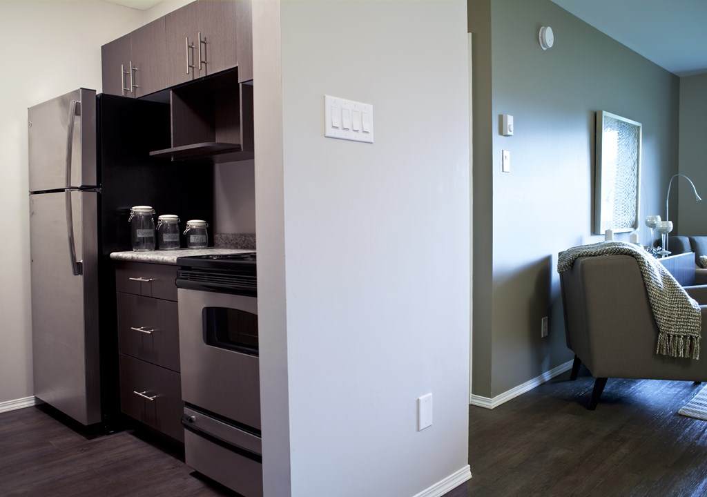 A kitchen with a refrigerator, oven, and cabinets.