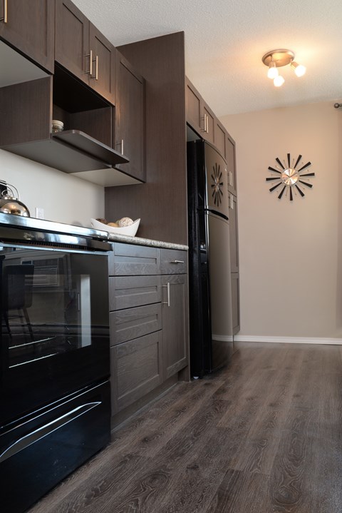 A modern kitchen with dark wood cabinets and a black stove top oven.