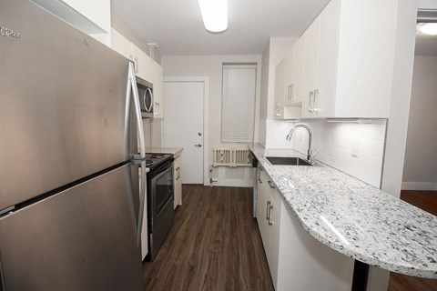 A kitchen with a stainless steel refrigerator and a granite countertop.