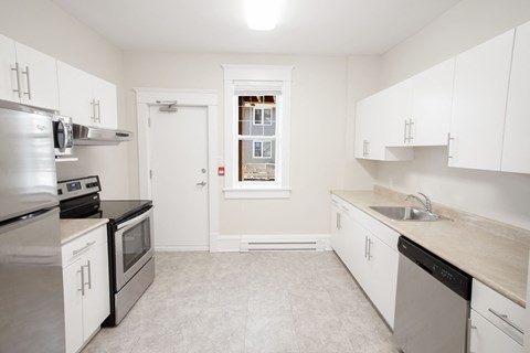 a kitchen with white cabinets and stainless steel appliances and a window