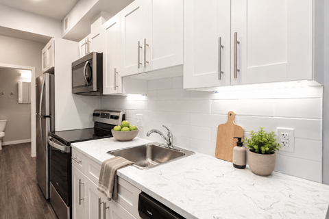 A kitchen with white cabinets and a marble countertop.
