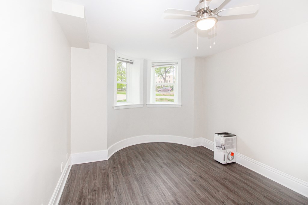 an empty room with white walls and a ceiling fan