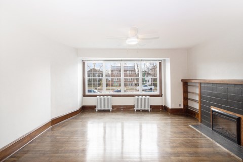 a living room with a large window and wooden floors and a fireplace