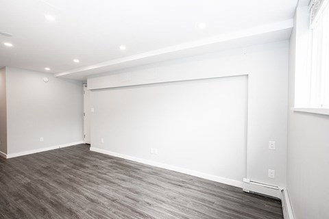 a living room with a white wall and wood floor