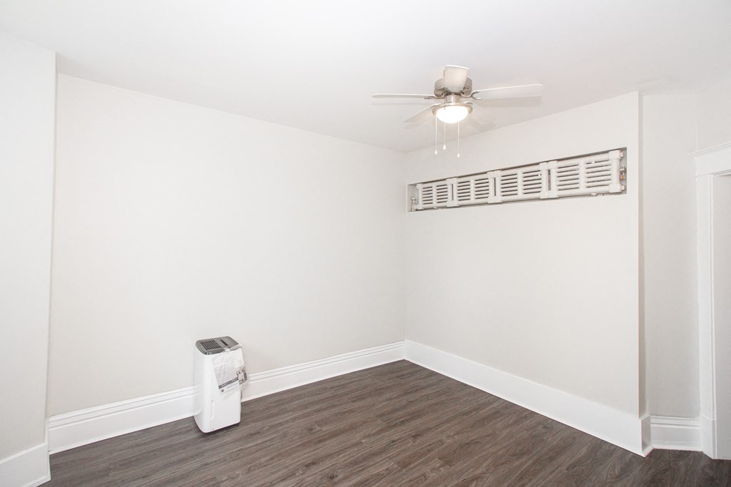 a living room with white walls and a ceiling fan