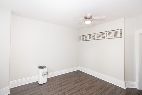 a living room with white walls and a ceiling fan