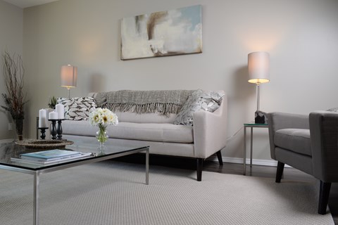 A living room with a couch, two chairs, a coffee table, and a painting on the wall.
